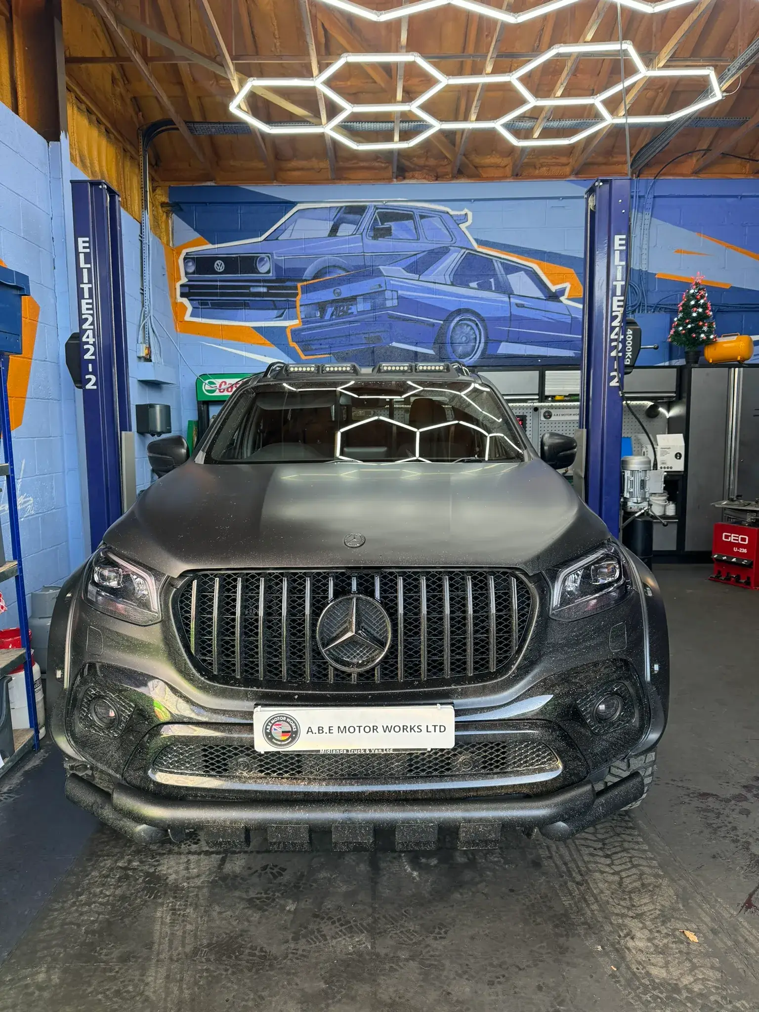 A car parked in a garage with a painting on the wall.
