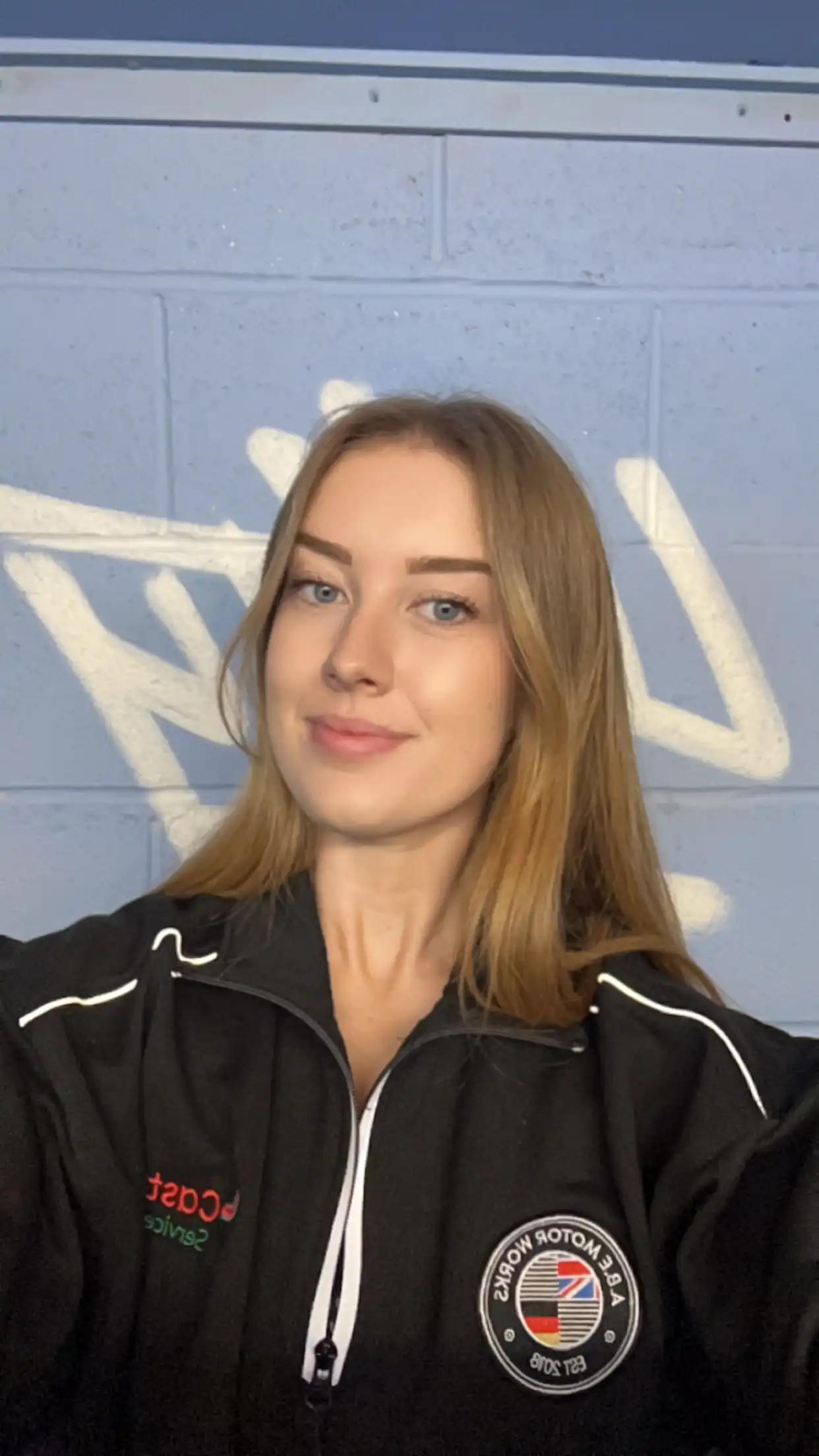 A woman in a black jacket holding a cell phone.